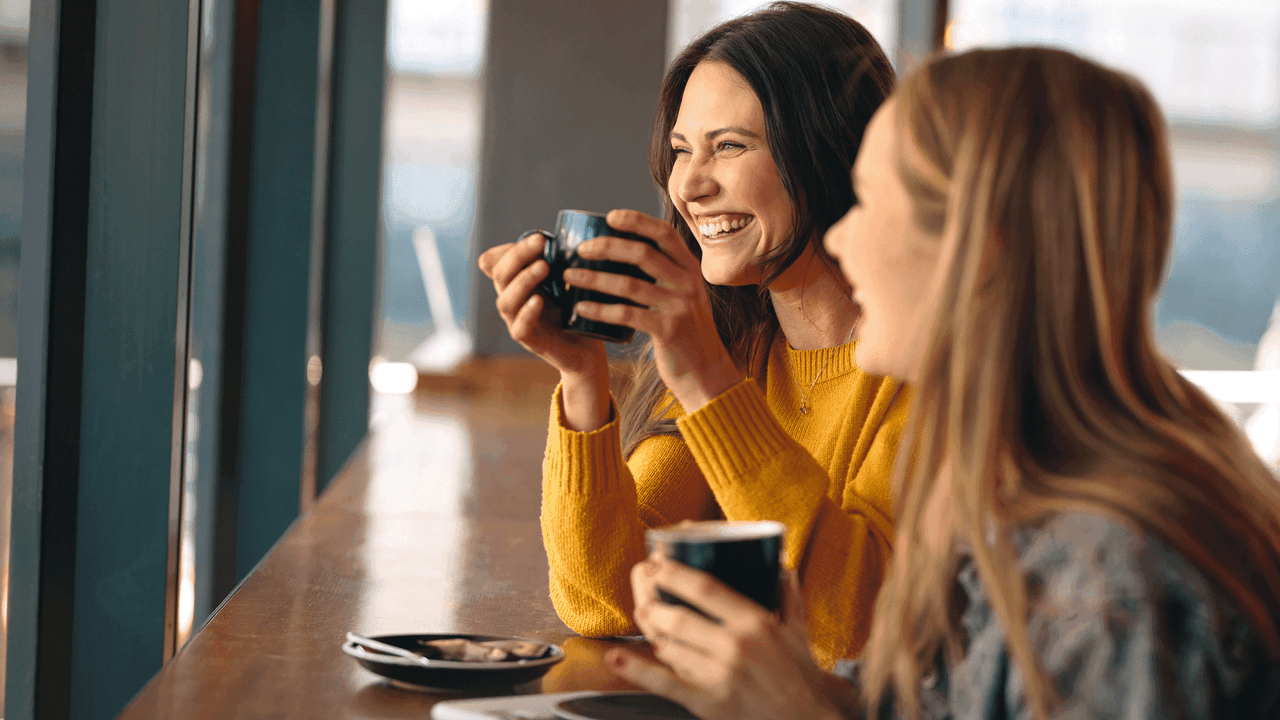 Kuvituskuvassa kaksi hyväntuulista ystävää on kahvilla.