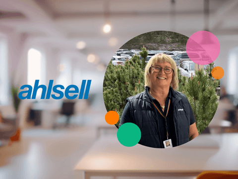 Ahlsellin logo vasemmalla. Oikealla hymyilevä Ahlsellin työntekijä ulkona mäntyjen ja autojen edessä. Taustalla on sumennettu toimistotila ja kuvan päällä värikkäitä graafisia ympyröitä