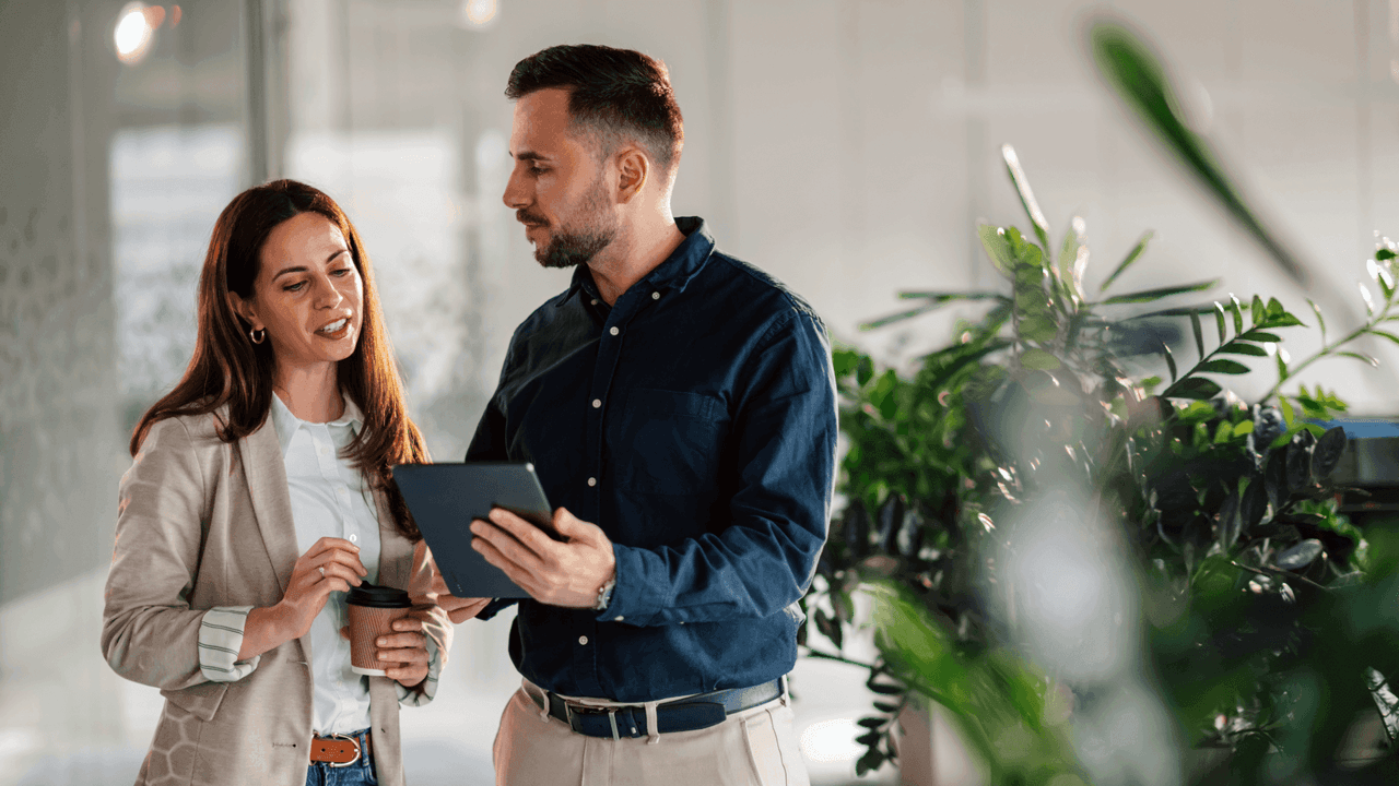 Nainen ja mies katsovat toimistolla tablettia