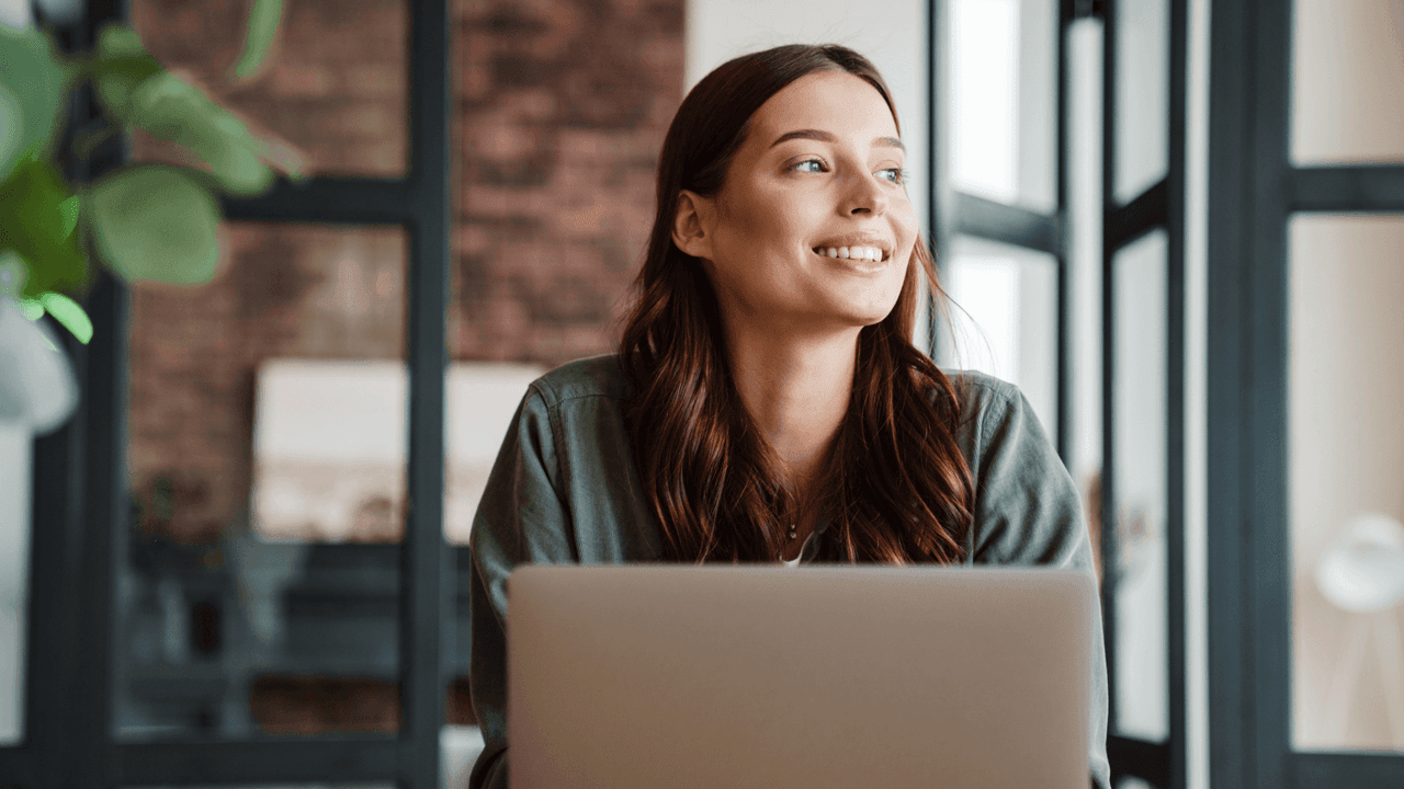 nainen hymyilee koneen ääressä