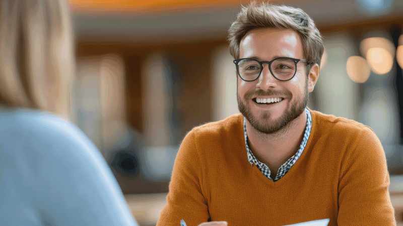 Kuvituskuvassa mies katsoo keskustelukumppania hymyillen.