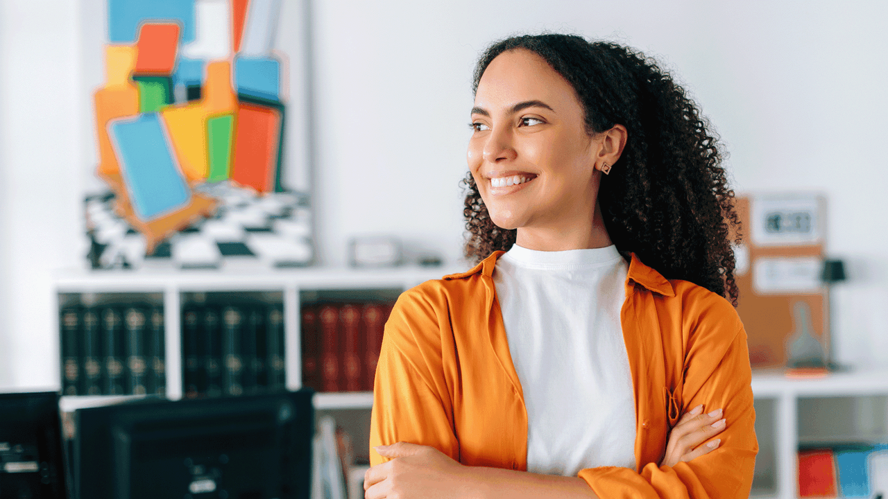 Kuvituskuvassa hymyilevä nainen on toimistossa.
