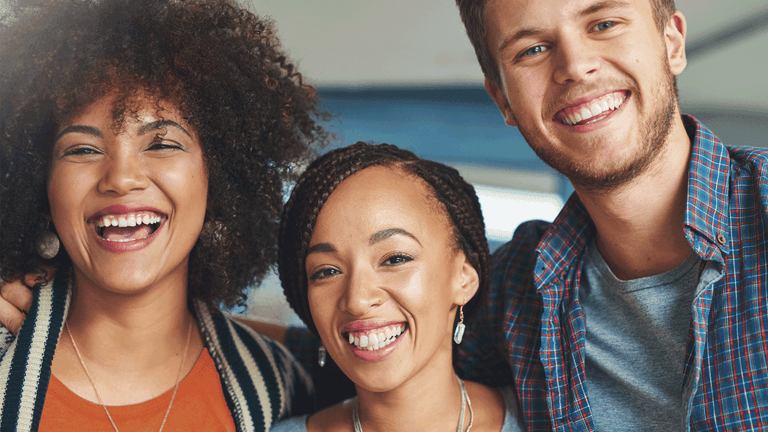 Kuvituskuvassa kolme kaverusta katsoo kameraan hymyillen leveästi.