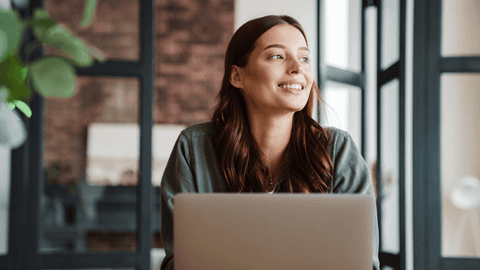 nainen hymyilee koneen ääressä